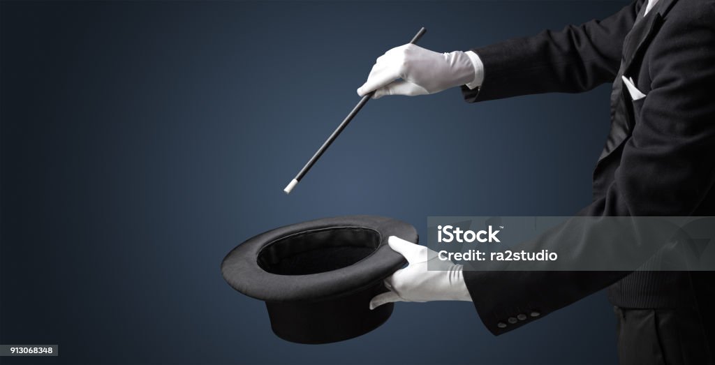 Illusionist hand want’s to conjure something Illusionist white hand wants to conjure with magic wand from a black cylinder something Magician Stock Photo