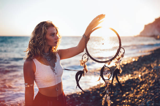 istock Beautiful woman in boho style holding dreamcatcher at the beach 913068406