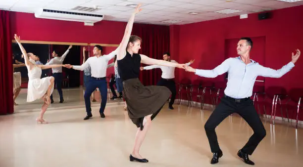 Photo of Cheerful people dancing lindy hop in pairs