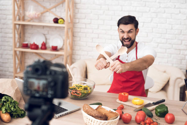istock Chef showing spatulas for culinary podcast shooting. Vegetables and kitchen utensils. 913068510
