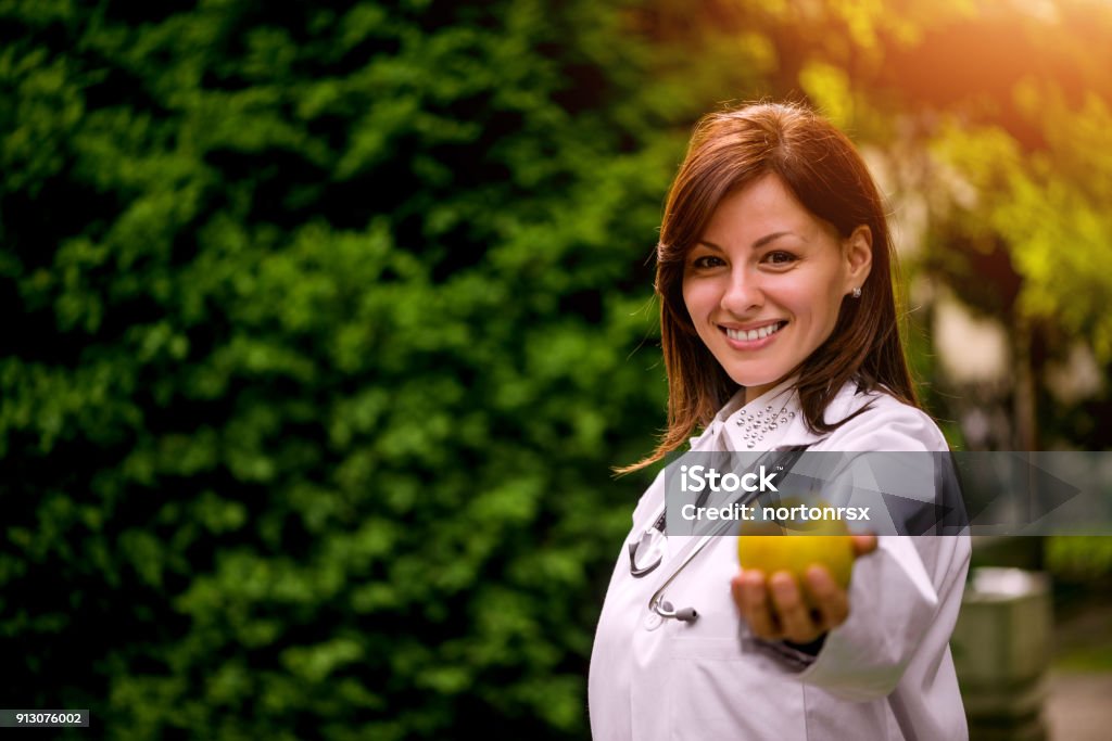 Female doctor offering apple Nutritionist Stock Photo