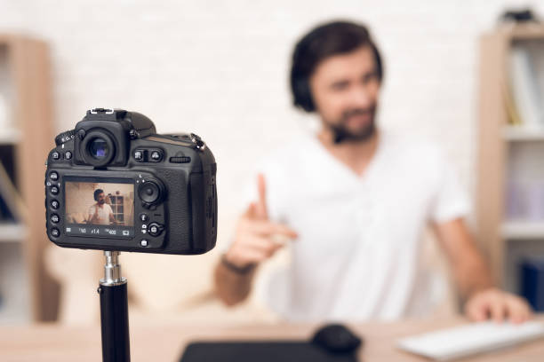 istock Camera shoots man podcaster posing for radio podcast. 913078384