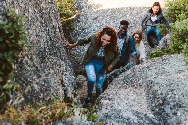 Woman climbing mountain rocks with friends