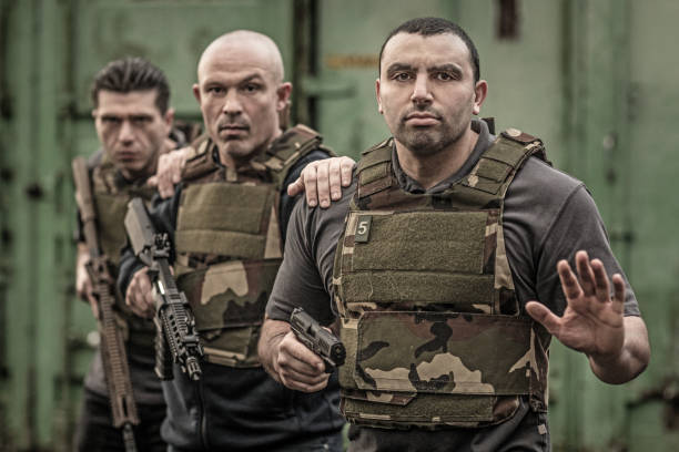 istock Krav Maga fighting group posing for team picture with weapons in grimy outdoor setting 913094216