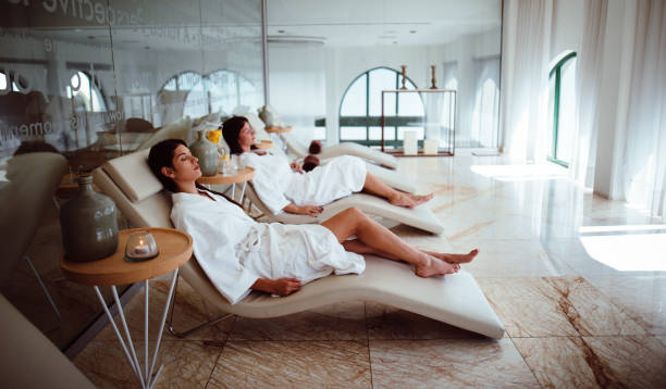 Young women in white robes relaxing at beauty spa centre Young hispanic female friends in white robes relaxing together at wellness hotel resort spa bathrobe photos stock pictures, royalty-free photos & images