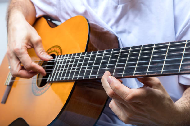 istock Young man's hand tuning acoustic guitar. 913105962