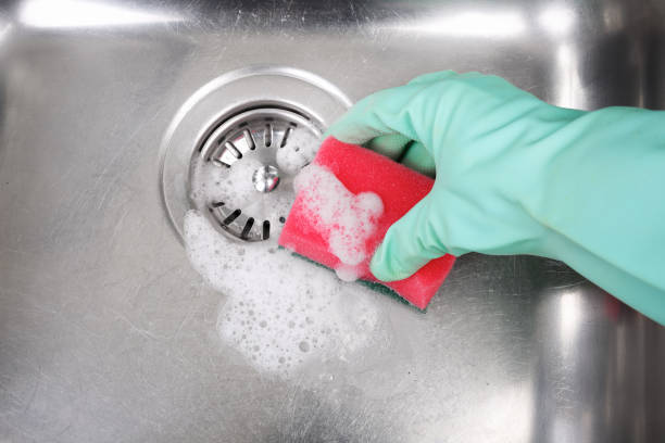 istock Hand with rubber glove holding colorful sponge for scrubbing sink 913106494