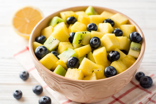 istock Fresh fruit salad with pineapple, mango, kiwi and blueberries on white wooden background. 913110224
