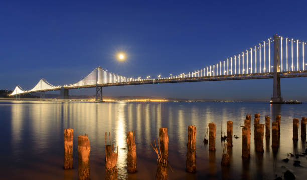 san francisco-oakland bay bridge bei vollmond steigt in der abenddämmerung. - san francisco county embarcadero center bay bridge built structure stock-fotos und bilder