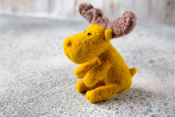 istock Felt toy moose sits on gray stone floor. 913159906