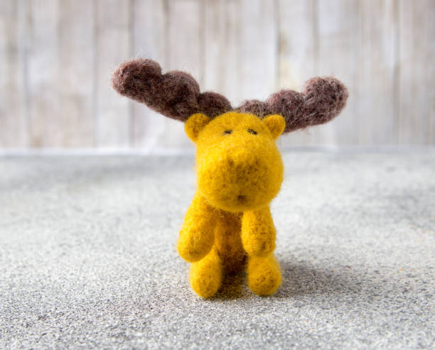 istock Felt toy moose sits on gray stone floor. 913160058