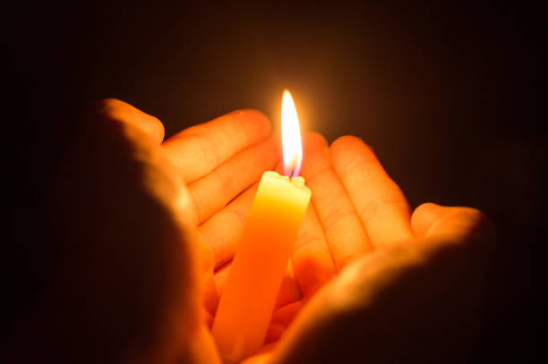 istock hands holding a burning candle in dark like a heart 913164840