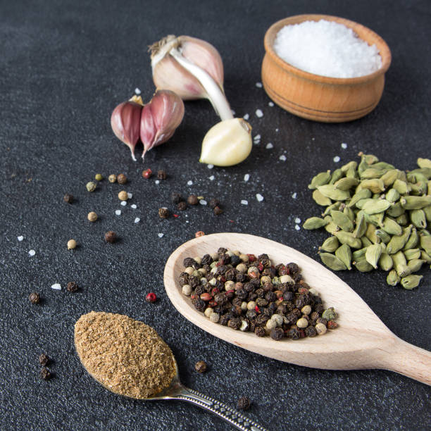 istock Cardamom, pepper, garlic, salt on a black stone background. Classic mixed spices for cooking. 913164846