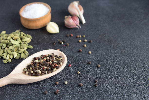 istock Cardamom, pepper, garlic, salt on black stone background. Classic mixed spices for cooking. 913165200
