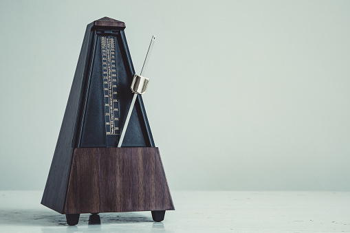 Color shot of a vintage metronome, on gray background.