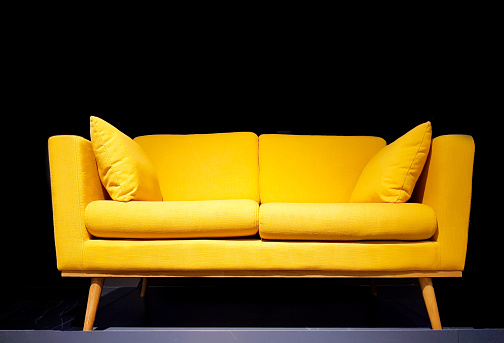 Yellow sofa in dark room with dim light background.