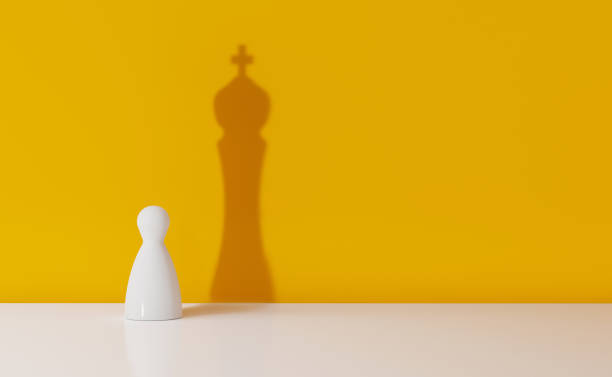 pedone degli scacchi che getta l'ombra di un re su sfondo giallo - ostentare foto e immagini stock