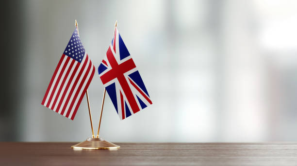 American And British Flag Pair On A Desk Over Defocused Background