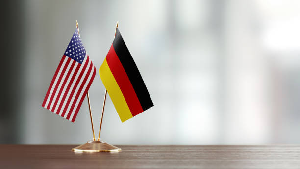 american and german flag pair on a desk over defocused background - german flag imagens e fotografias de stock