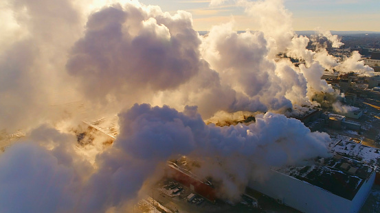 Aerial view of dense factory emissions, steam, smoke, possible air pollution.