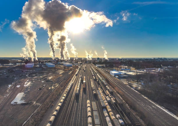 Rail yard full of trains under industrial emissions, sunrise. Aerial view.