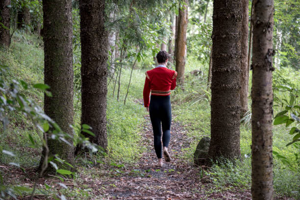 istock Young man in Red Spanish top walks away from camera down forest path 913178790