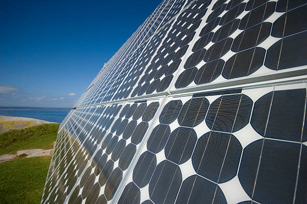 A solar panel with land and water in the background  stock photo