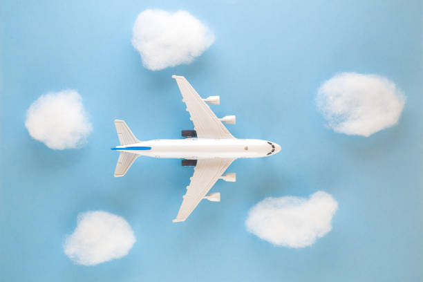 istock High angle view of airplane toy and clouds on blue sky background 913192852