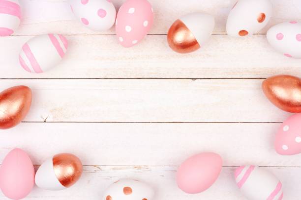 istock Easter egg frame. Rose gold, pink and white on white wood. 913199984