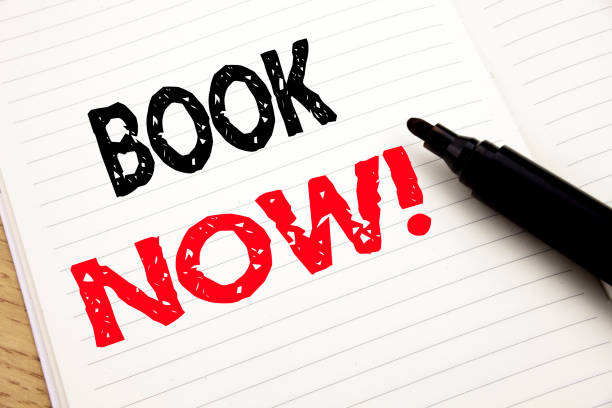 istock Book Now. Business concept for Reservation Booking written on notebook with copy space on book background with marker pen 913207018