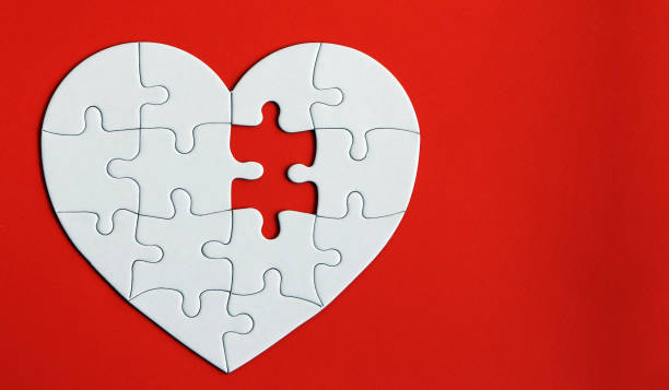 Heart puzzle on the red background. A missing piece of the heart puzzle. stock photo