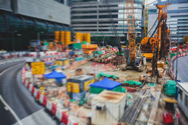 A large construction site in the city, the process of massive buliding construction with heavy vehicle at work, excavator, elevating crane and bulldozer