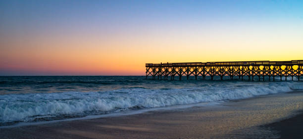 Dramatic Sky Over the Pier A dramatic sky erupts over an ocean fishing pier at Wrightsville Beach, NC. wilmington north carolina stock pictures, royalty-free photos & images