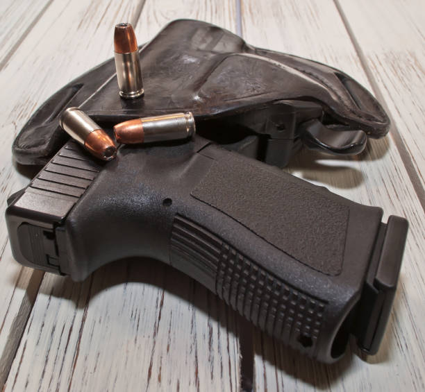 istock A holstered black pistol with several bullets on a wooden table 913223662