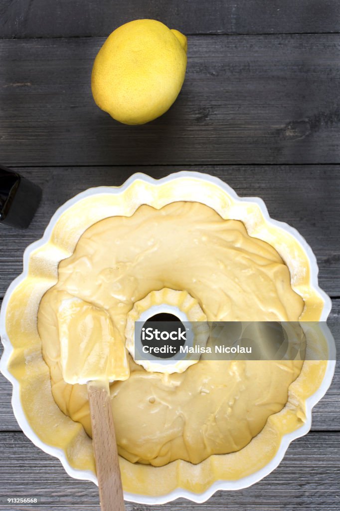 Preparing batter for a lemon cake in a bundt pan Preparation of batter for a lemon cake in a yellow bundt pan with a spatula on a rustic table top Cream - Dairy Product Stock Photo