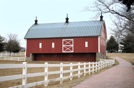 Countryside view of a large barn and out building with a silo in this agricultural landscape.