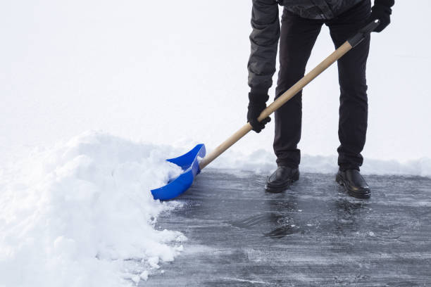 mann reinigung schnee mit blauen schaufel aus eisfläche zum schlittschuhlaufen. winter-routine-konzept. - winterdienst stock-fotos und bilder