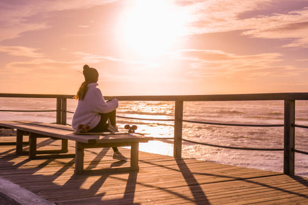istock Girl with skateboard watching the ocean 913279446