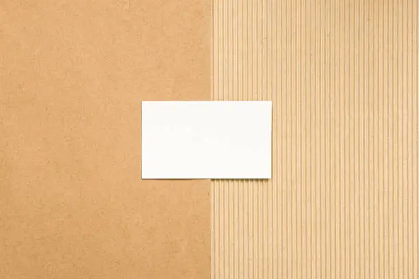Empty white business card on brown ribbed and recycled paper.