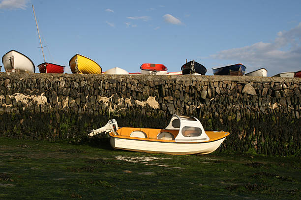 This is a horizontal, color photograph of colorful sailboats moored in the bay of Howth, Ireland during sunset.
