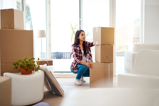 Full length shot of an attractive young woman stacking boxes while moving house