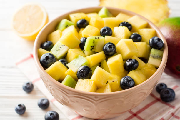 istock Fresh fruit salad with pineapple, mango, kiwi and blueberries on white wooden background. 913291636