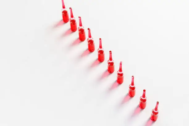 Medical ampoules with a red injection, on a white background, top view