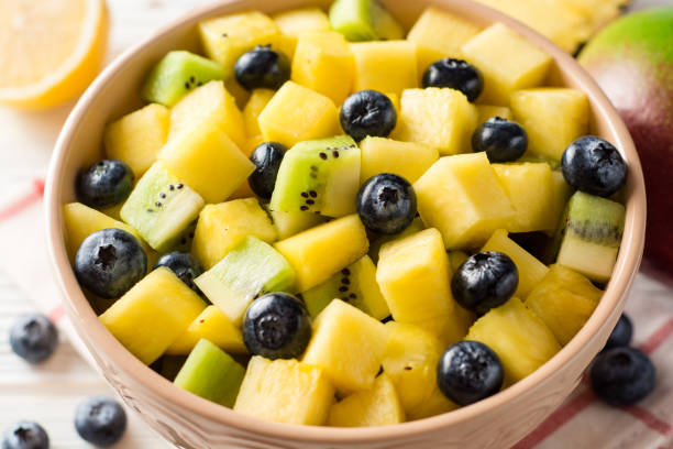 istock Fresh fruit salad with pineapple, mango, kiwi and blueberries on white wooden background. 913291768