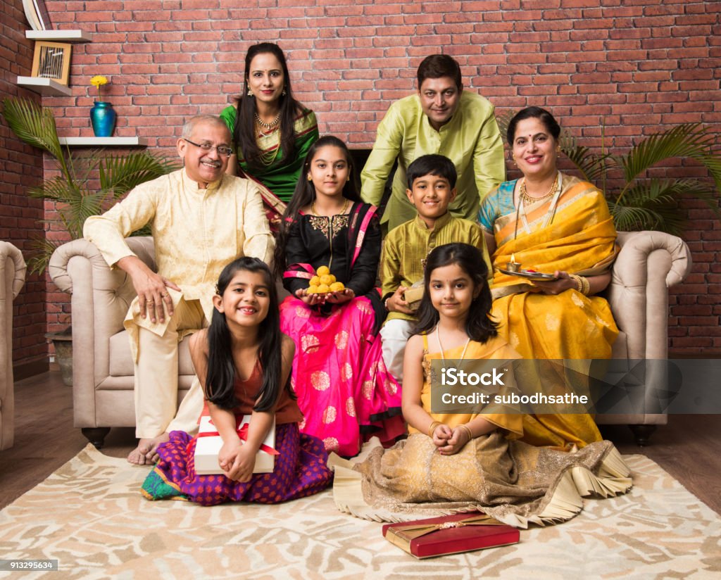 Retrato de familia feliz India en ropa tradicional sentado en el sofá de interior - Foto de stock de Familia libre de derechos