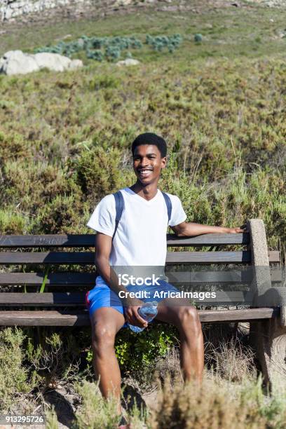 Young Man Sitting On A Bench Smiling Stock Photo - Download Image Now - Adult, Adults Only, Africa