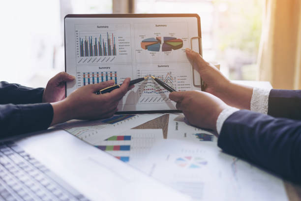 istock financial Image of two  business people pointing at business document presentation summary report , during discussion at meeting , Notebook on wood table 913295938