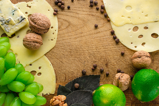 Blue cheese with grapes, nuts and limes on wooden background