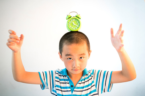 asian boy with green clock on his head with white wall as background