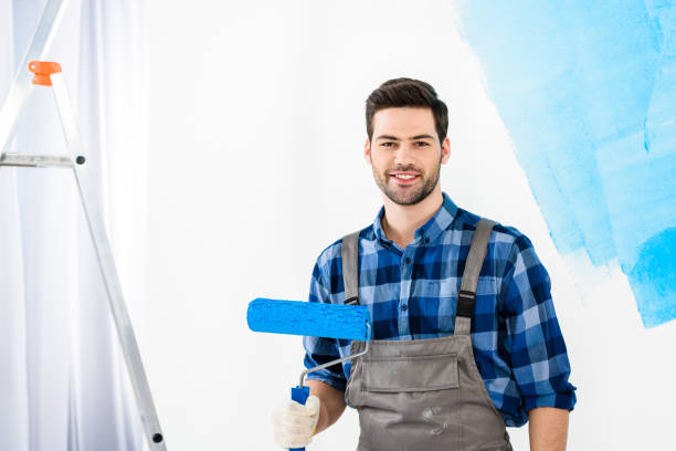 istock smiling man standing with paint roller brush and looking at camera 913311418
